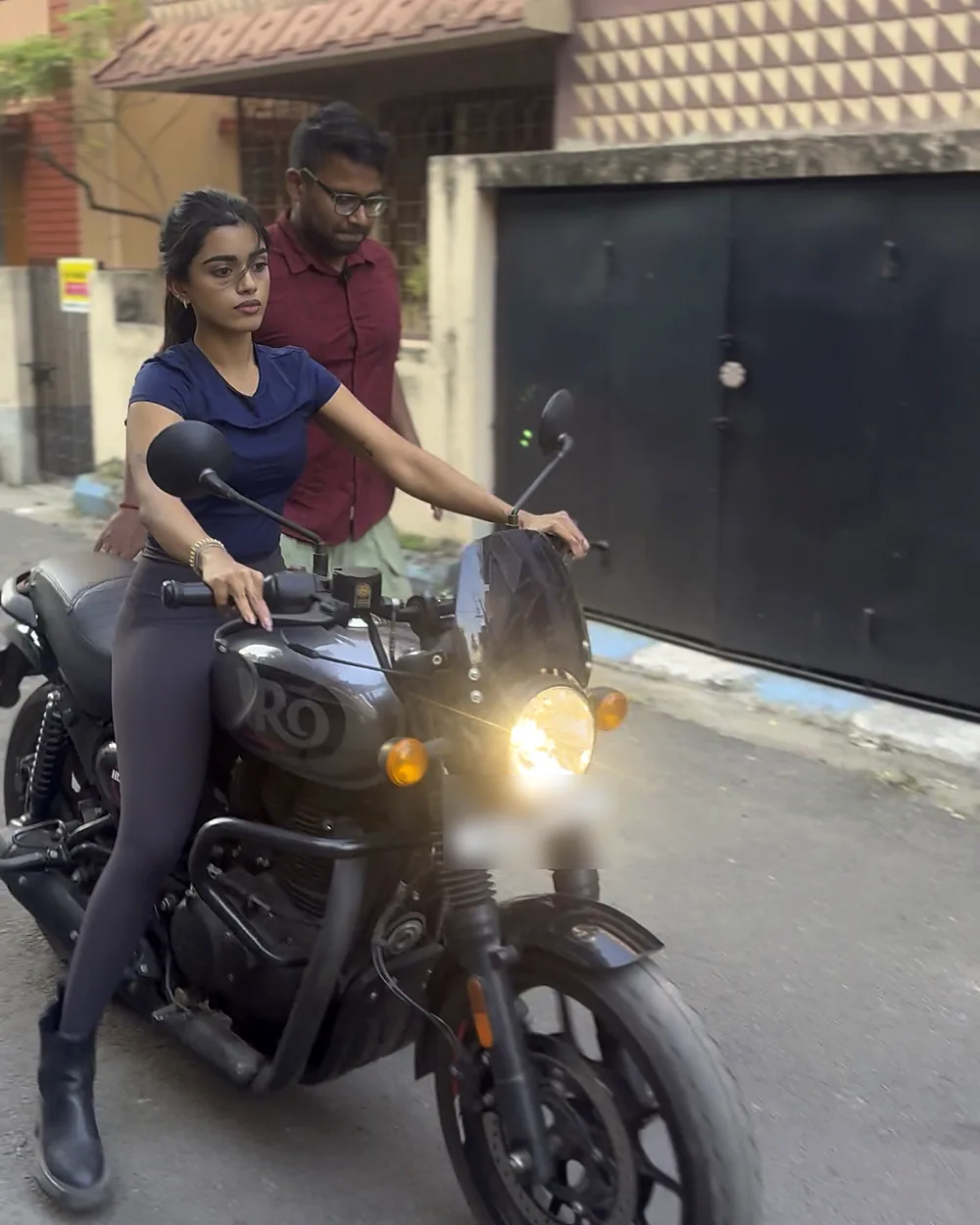 Woman riding a motorcycle while her trainer walks beside her